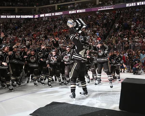 Hershey Bears players celebrating with the Calder Cup on the ice.