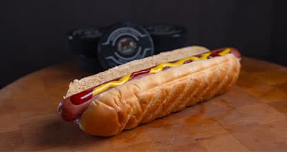 A hot dog topped with mustard placed on a table.