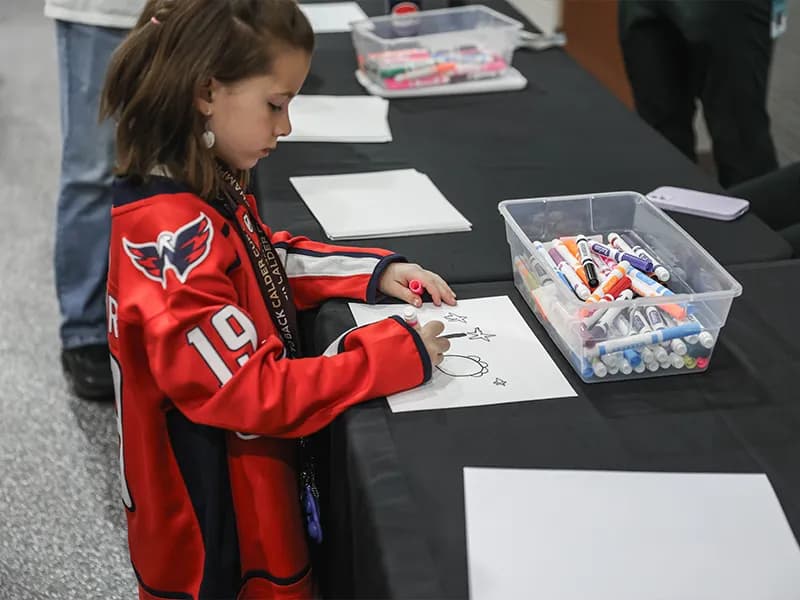 A young fan drawing at a table at South End Fan Zone.