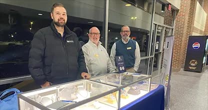 Sponsor representatives hosting an activation table on the arena concourse.